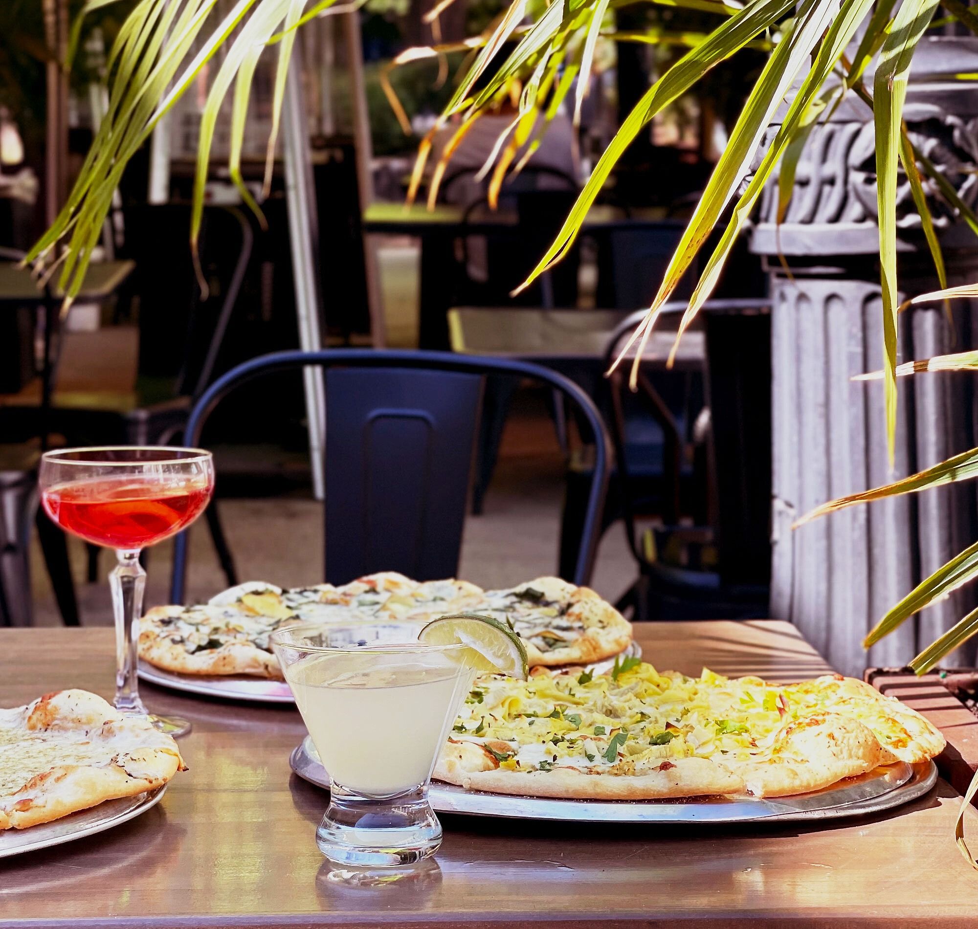 Sidewalk patio at Eduardo's Enoteca Gold Coast with tables, umbrellas, and greenery